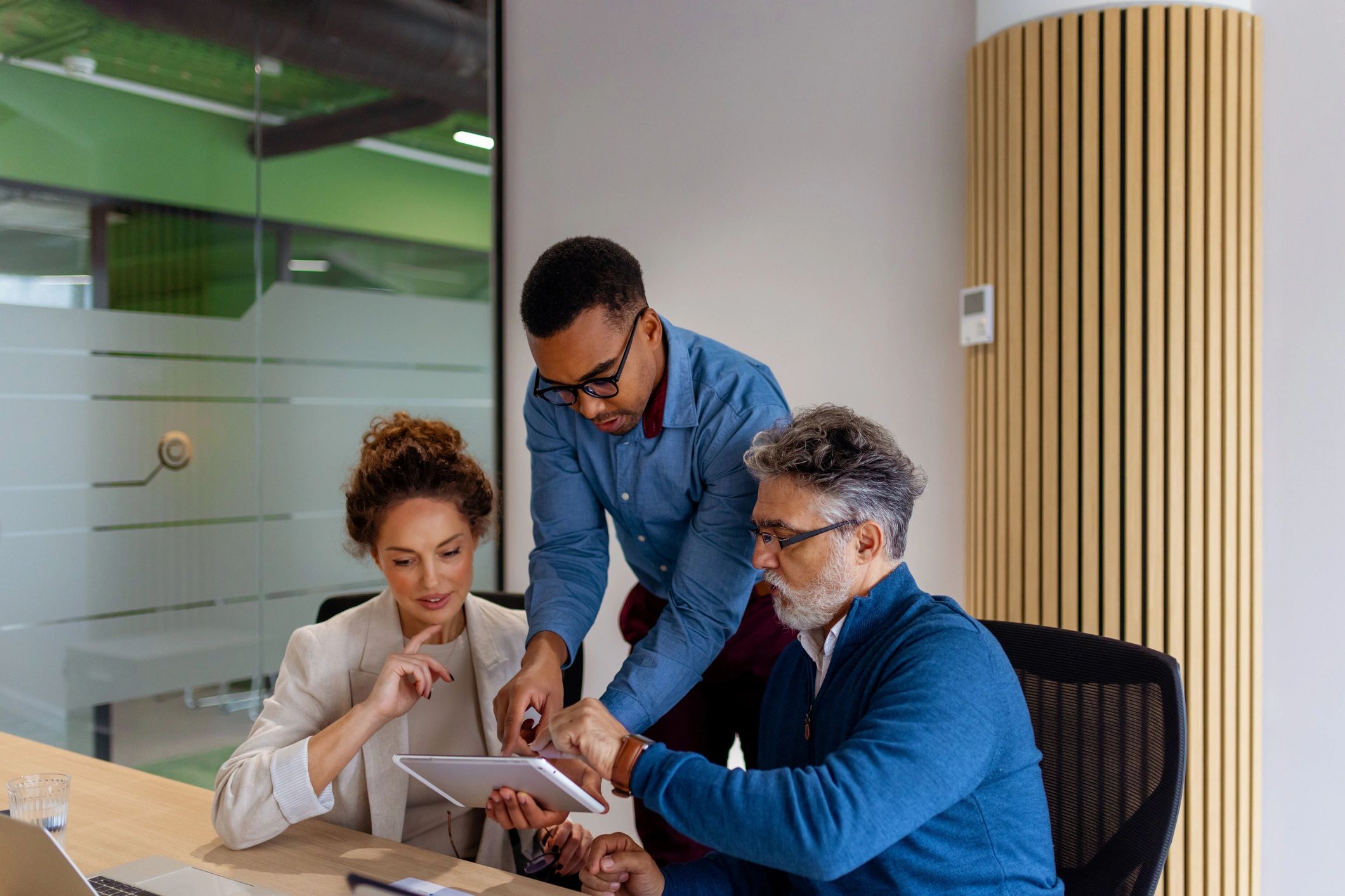 Technology professionals collaborating on a tablet in a modern office